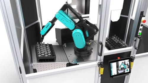 Industrieroboter in geschlossener Zelle bestückt Werkstücke automatisch.