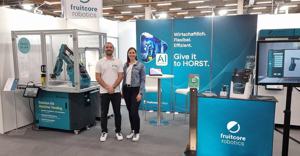 Mann und Frau stehen vor einem Messestand 